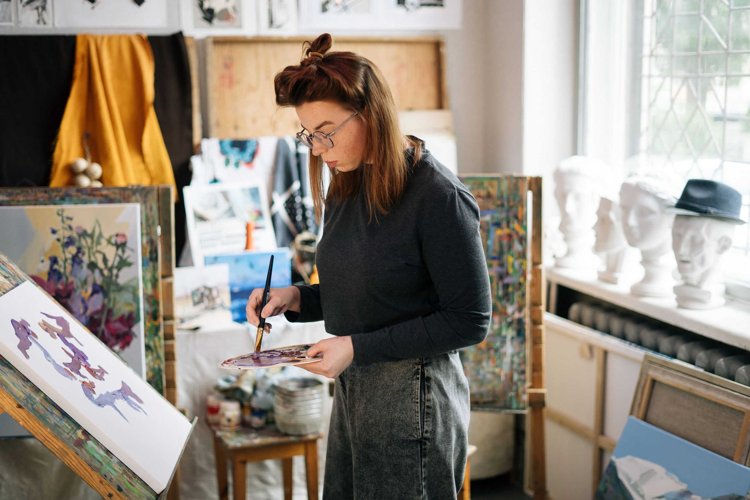 Een vrouw werkt aan een schilderij in haar atelier